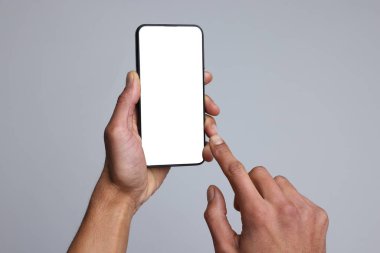 Açık gri arka planda boş ekranlı akıllı telefon tutan adam, yakın plan. Tasarım için model