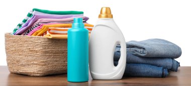 Çamaşır sepetinde beyaz arka planda çamaşır ve deterjan var.