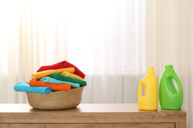 İçerideki ahşap dolapta havlu ve deterjan dolu çamaşır sepeti.