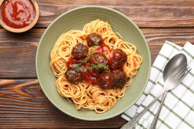Köfteli lezzetli makarna ahşap masada servis ediliyor.
