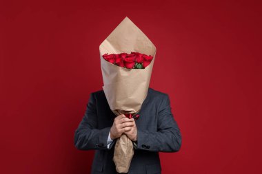 Sevgililer Günü. Kırmızı arka planda gül buketi olan bir adam.