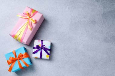 Gri masa üzerinde güzel paketlenmiş hediyeler, düz yatış. Metin için boşluk