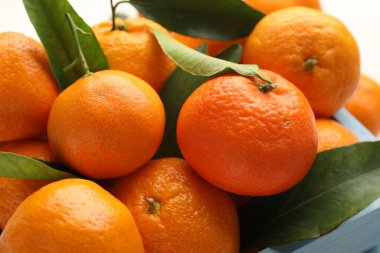 Taze mandalina ve yeşil yapraklar masada, yakın plan.