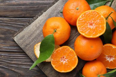 Taze mandalinalar ve ahşap masa üzerinde yeşil yapraklar, üst manzara. Metin için boşluk