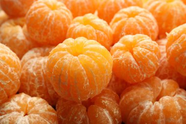 Arka plan olarak birçok olgun soyulmuş mandalina, yakın plan