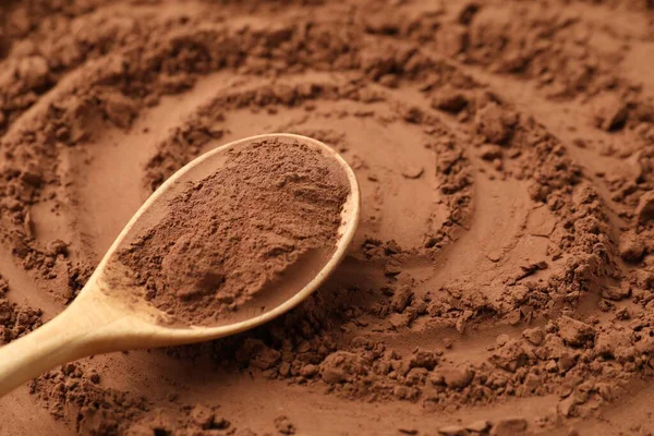 Arkaplan olarak kakao tozu ve tahta kaşık, yakın plan.