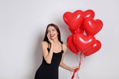 Sevgililer Günü. Beyaz arka planda kalp şeklinde balonları olan güzel bir kadın.