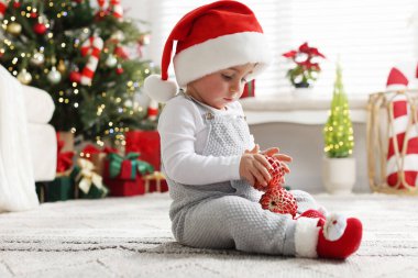 Noel Baba şapkalı küçük çocuk yerde mücevherlerle Noel için dekore edilmiş bir odada