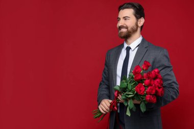 Sevgililer Günü. Kırmızı arka planda gül buketi olan yakışıklı bir adam. Metin için boşluk