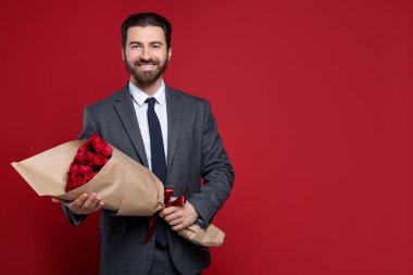 St. Valentine's Day.Man with bouquet of roses on red background. Space for text