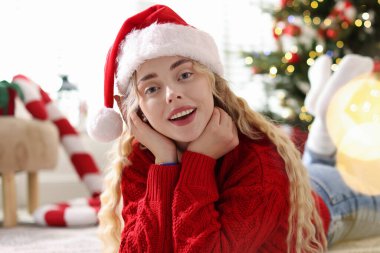 Noel Baba şapkalı ve süveterli gülümseyen kadın evdeki bulanık ışıklara karşı, bokeh etkisi. Mutlu Noeller ve mutlu yıllar.