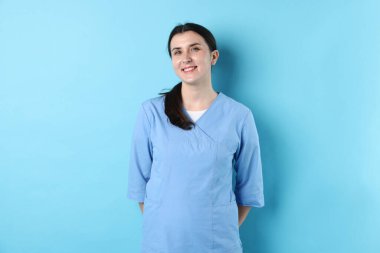 Açık mavi arka planda tıp üniformalı bir doktor.