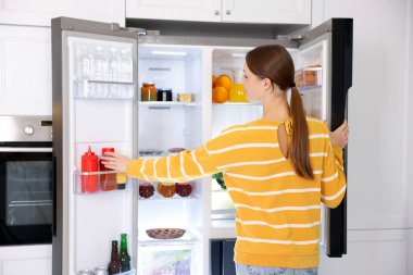 Mutfaktaki buzdolabından sos alan kadın.