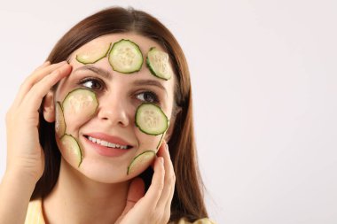 Yüzünde salatalık dilimleri olan bir kadın beyaz arka planda, mesaj için yer var.