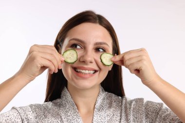 Beyaz arka planda salatalık dilimleri olan bir kadın.