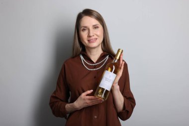 Açık gri arka planda beyaz şarap şişesi olan profesyonel şarap garsonu.