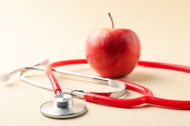 Bej arka planda olgun elma ve steteskop, seçici odak