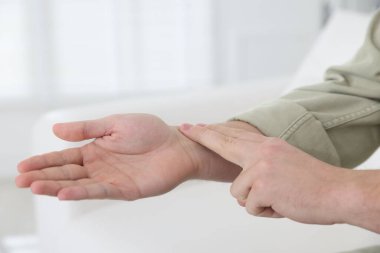 Adam nabzını evde kontrol ediyor, yakın plan. Metin için boşluk