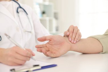 Doktor masadaki parmaklarıyla adamın nabzını kontrol ediyor.