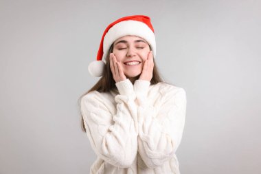 Işıklı arka planda Noel Baba şapkası olan güzel bir kadın. Noel sezonu