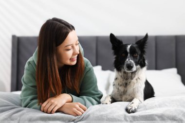 Evde yatağında Collie köpeği olan bir kadın.