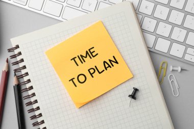 Plan yapma zamanı. Kağıt not, bilgisayar klavyesi ve kırtasiye sehpası düz.