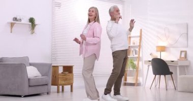 Mutlu yaşlı çift evde dans ediyor.