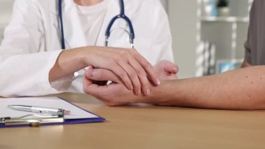 Doktor masadaki parmaklarıyla adamın nabzını kontrol ediyor.