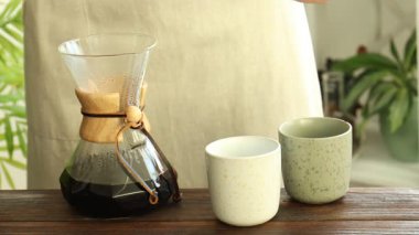 İçerideki ahşap masada fincanlara lezzetli kahve döken kadın, yakın plan.