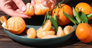Ahşap masada olgun mandalinalı bir kadın, yakın plan.