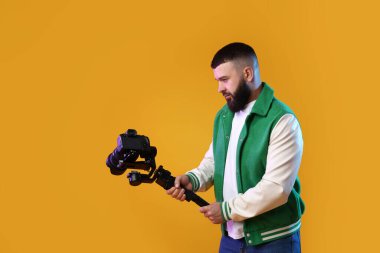 Kameraman sarı arka planda kameralı titreşimli dengeleyici kullanıyor. Metin için boşluk