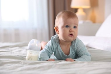 Evde yatağında biberonla beslenen tatlı bir bebek. Metin için boşluk