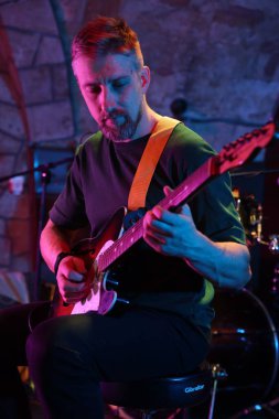 Sahnede gitar çalan yakışıklı adam.