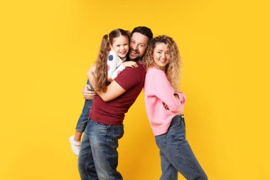 Mutlu aile kucaklaşması ve sarı arka planda poz.