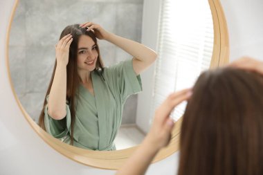 Evde aynanın yanında pudra gibi pudra kullanan bir kadın.