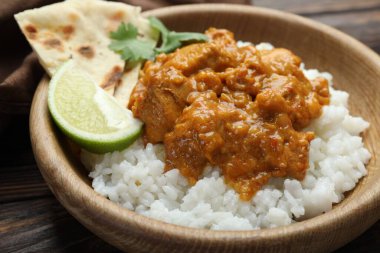 Pirinçli tavuk tikka masala, kişniş, kireç ve lavaş ahşap masada, yakın plan.