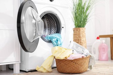 Çamaşır sepetinin yanında çamaşır makinesi var.