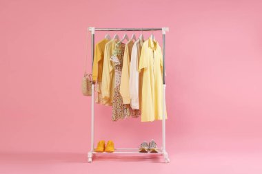 Pembe arka planda farklı şık kıyafetler, çanta ve ayakkabılar.