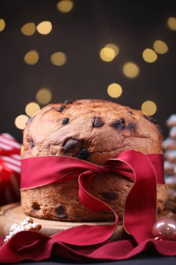 Noel yemeği. Lezzetli Panettone keki, zencefilli kurabiye ve masanın üzerindeki bulanık ışıklara karşı dekor, yakın plan. Bokeh etkisi