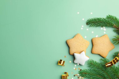 Kurabiyeler, köknar dalları ve yeşil arka planda konfeti olan güzel bir Noel kompozisyonu. Metin için boşluk