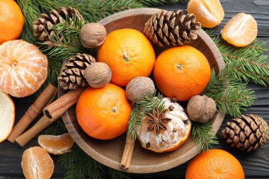 Olgun mandalinalar, baharatlar, cevizler, köknar ağacı dalları ve kozalaklar ahşap masa üzerinde, düz yatıyordu.