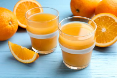 Taze portakal suyu ve açık mavi ahşap masada meyveler, yakın plan.