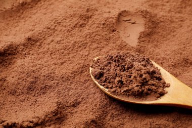 Arkaplan olarak kakao tozu ve tahta kaşık, yakın plan.