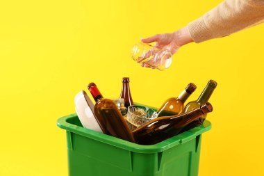 Turuncu arka plandaki çöp kutusuna çöp atan kadın, yakın plan. Atık sıralama