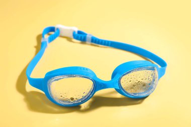 Sarı arka planda mavi yüzme gözlükleri, yakın plan.