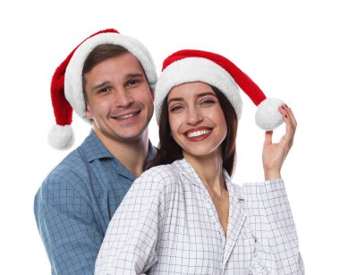 Beyaz arka planda Noel Baba şapkalı ve pijamalı mutlu bir çift. Noel atmosferi