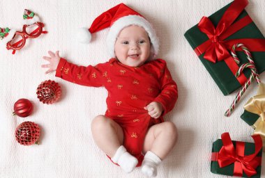 Noel Baba şapkalı şirin küçük bebek, Noel hediyeleri ve beyaz battaniyeli dekor, düz uzanma