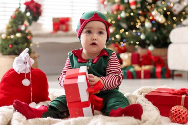 Evde hediye ve çanta taşıyan elf kostümlü şirin bir bebek. Noel sezonu