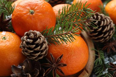 Olgun mandalinalar, baharatlar, köknar ağacı dalları ve koniler masada, yakın plan.