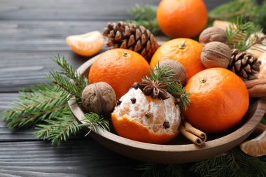 Olgun mandalinalar, baharatlar, cevizler, köknar ağacı dalları ve tahta masanın üzerindeki koniler, yakın plan.